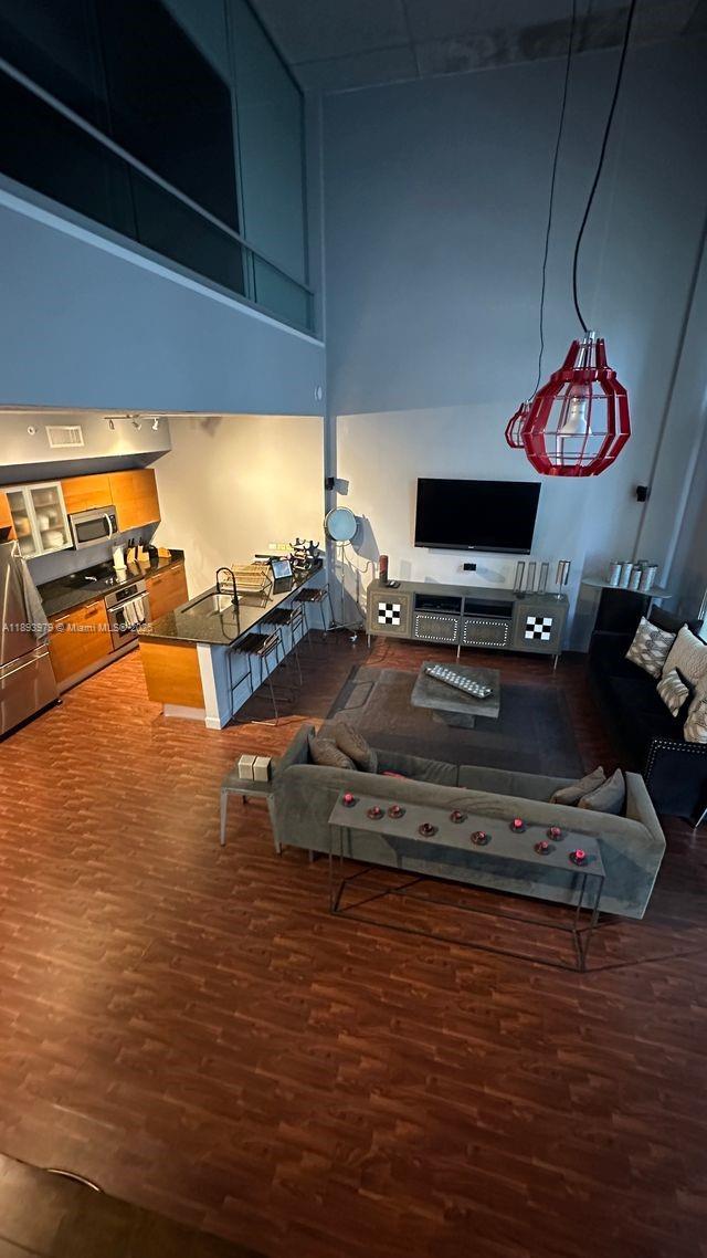 An open-concept living room and kitchen featuring high ceilings, wood flooring, and modern furnishings — 3449 NE 1st Ave # L43, Miami FL 33137, MIAMI, FL