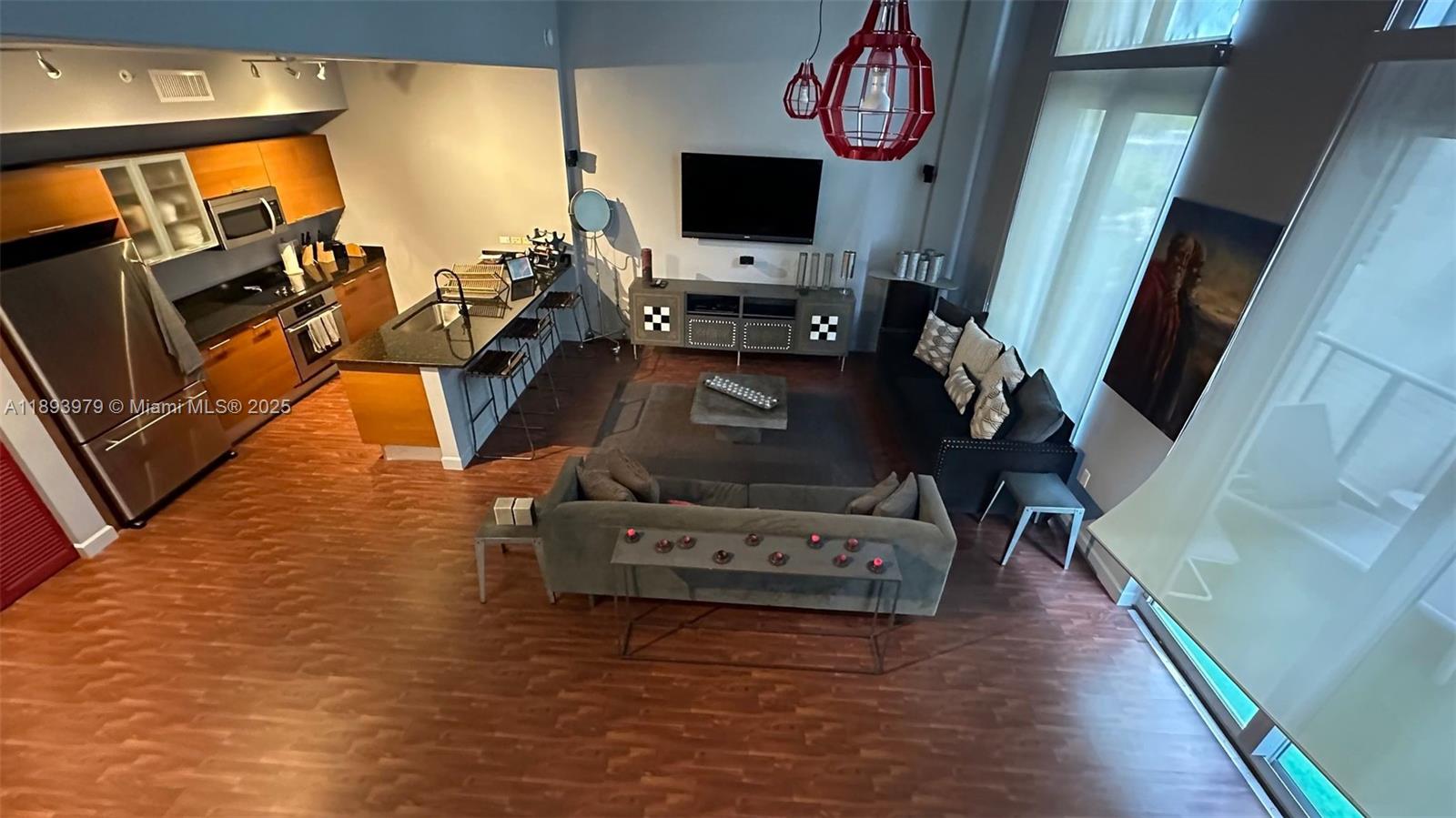 This open-concept living room and kitchen features wood-look flooring, a kitchen island, and high ceilings — 3449 NE 1st Ave # L43, Miami FL 33137, MIAMI, FL