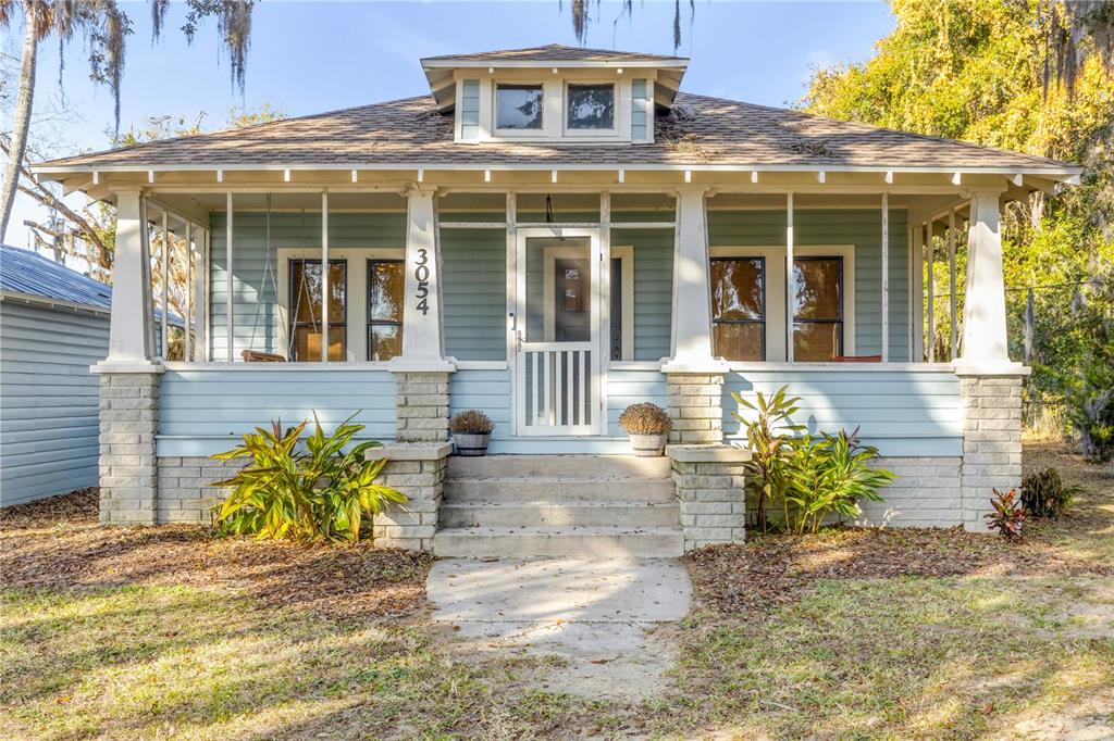 A light blue bungalow features a screened front porch, stone pillars, and a dormer window — 3054 N DIXIE FREEWAY, NEW SMYRNA BEACH, FL