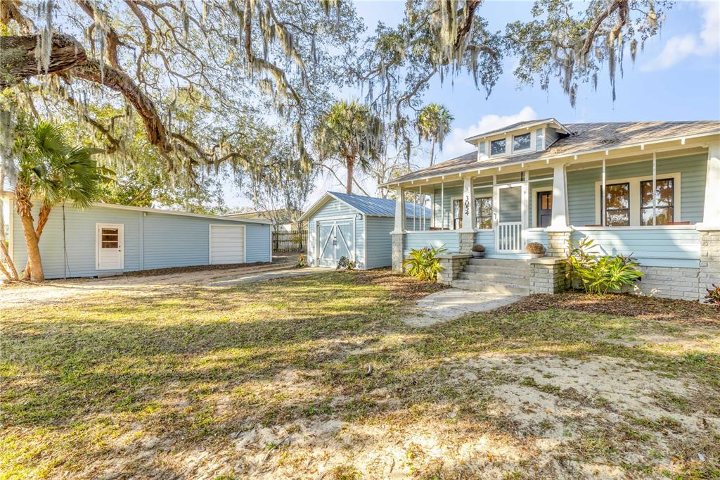 A light blue house with a front porch and two detached garages on a lawn — 3054 N DIXIE FREEWAY, NEW SMYRNA BEACH, FL