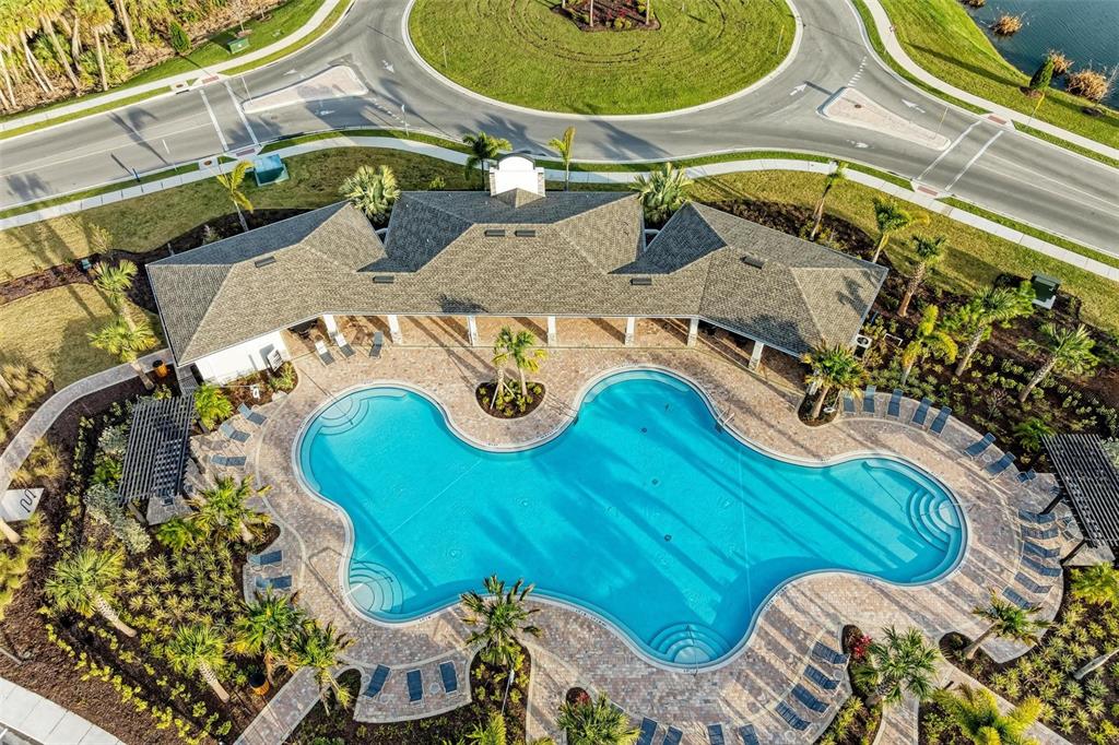 An aerial view shows a community swimming pool with a surrounding patio and clubhouse building — 4120 SILVER STRAND TRAIL, PALMETTO, FL