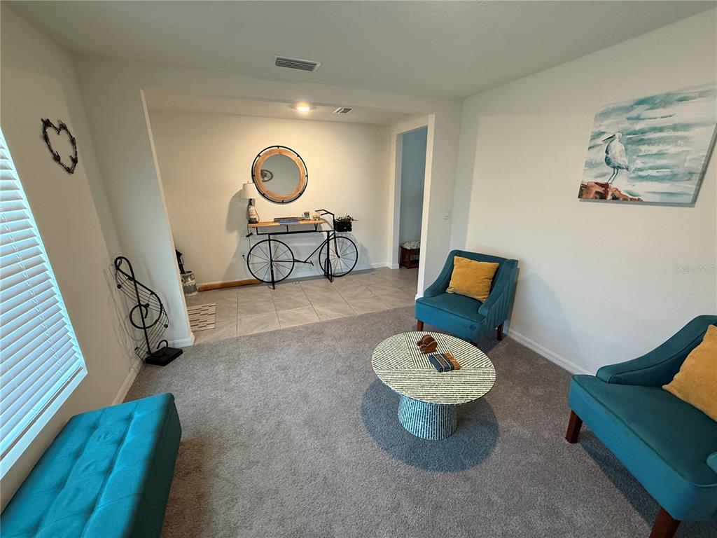A living room features teal armchairs, a round patterned coffee table, and a bicycle console table — 4120 SILVER STRAND TRAIL, PALMETTO, FL