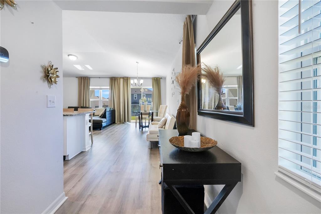A view from a hallway into an open-concept living area with wood-look flooring — 9231 WESTSIDE HILLS DRIVE, DAVENPORT, FL