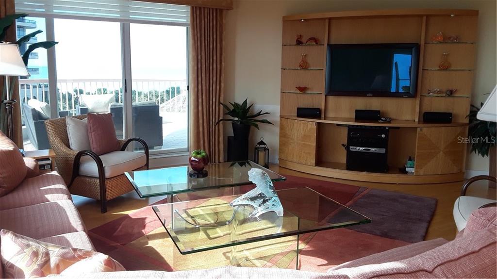 A living room features a large entertainment center, glass coffee tables, and a balcony view — 455 LONGBOAT CLUB ROAD UNIT 401, LONGBOAT KEY, FL