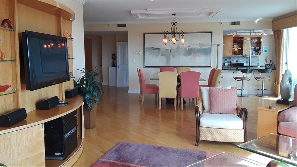 A living and dining area features light wood floors, a television console, and colorful chairs — 455 LONGBOAT CLUB ROAD UNIT 401, LONGBOAT KEY, FL