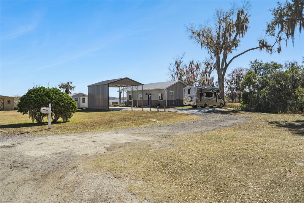 A gravel driveway leads to a house with a metal carport and a parked RV — 645 CR 485A, LAKE PANASOFFKEE, FL