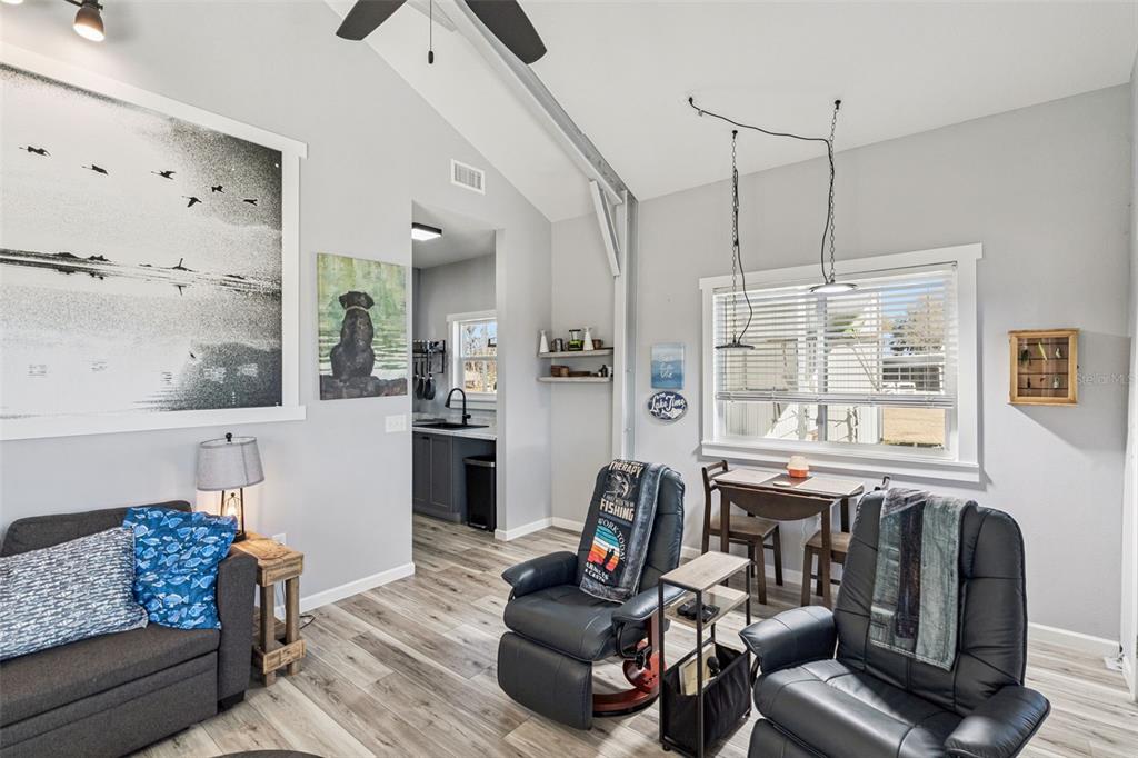 A living room with gray walls, wood-look flooring, two black recliners, and a small dining area — 645 CR 485A, LAKE PANASOFFKEE, FL