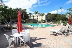 A swimming pool with lounge chairs and a patio table sits outside a residential building — 1068 LOTUS PARKWAY UNIT 833, ALTAMONTE SPRINGS, FL