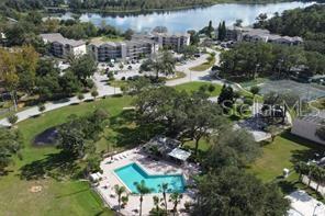 An aerial view shows an apartment complex with a swimming pool, tennis courts, and lake — 1068 LOTUS PARKWAY UNIT 833, ALTAMONTE SPRINGS, FL