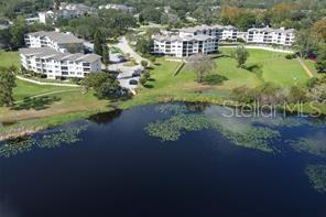 An aerial view shows apartment buildings situated near a lake with lily pads — 1068 LOTUS PARKWAY UNIT 833, ALTAMONTE SPRINGS, FL