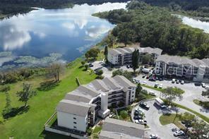 An aerial view shows multi-story apartment buildings situated next to a large lake and trees — 1068 LOTUS PARKWAY UNIT 833, ALTAMONTE SPRINGS, FL