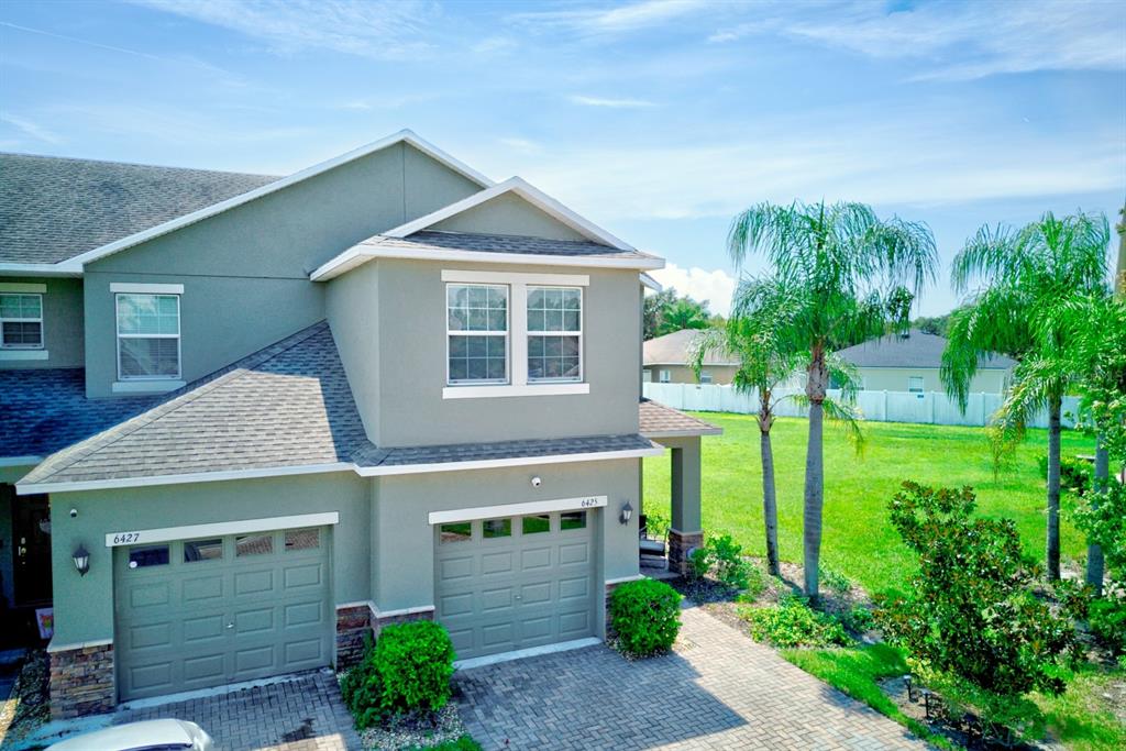 An exterior view of a two-story townhouse with two garage doors and a paved driveway — 6425 TORRINGTON CIRCLE, LAKELAND, FL