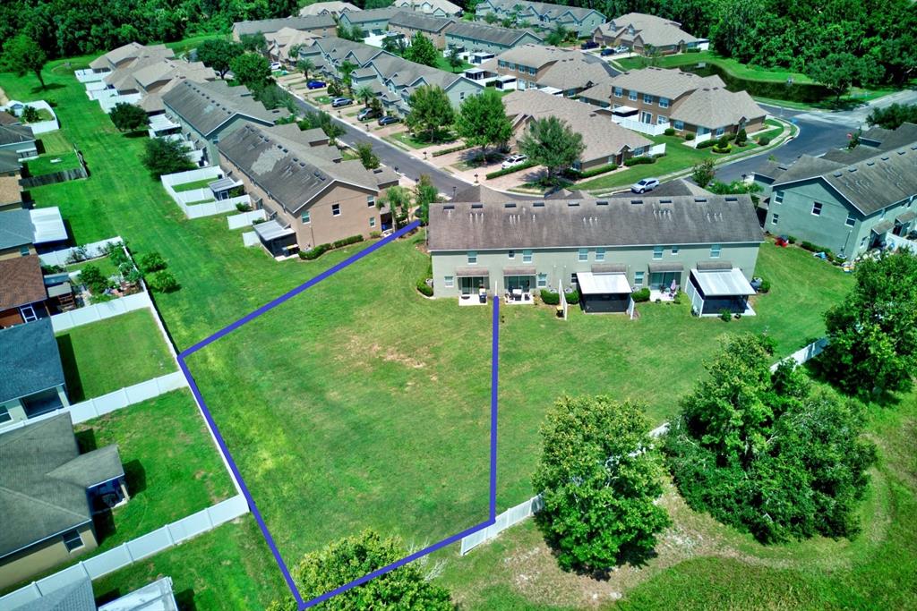 An aerial view shows a residential townhouse with a large, outlined grassy backyard — 6425 TORRINGTON CIRCLE, LAKELAND, FL