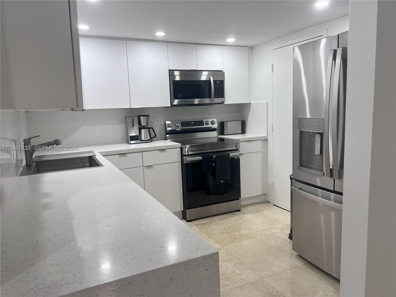 A modern kitchen features white cabinetry, stainless steel appliances, and light-colored quartz countertops — 800 West Ave # 635, Miami Beach FL 33139, MIAMI BEACH, FL