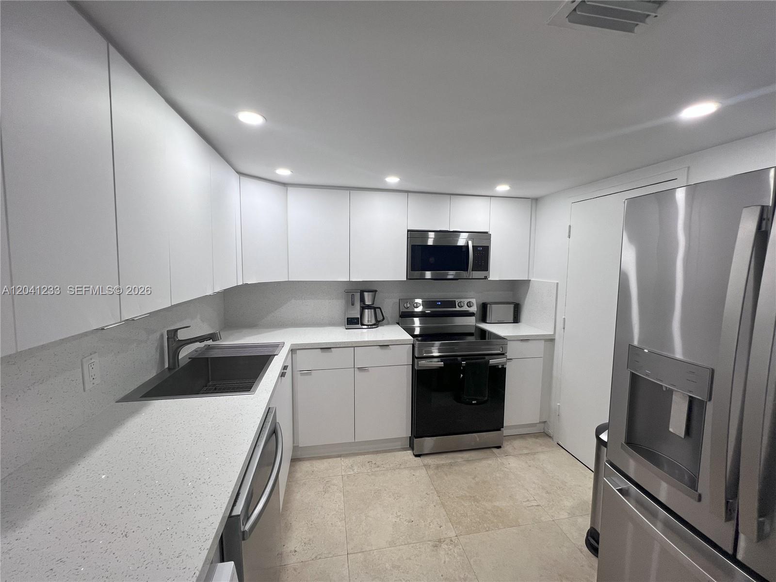 A modern kitchen features white cabinets, stainless steel appliances, and light-colored quartz countertops — 800 West Ave # 635, Miami Beach FL 33139, MIAMI BEACH, FL