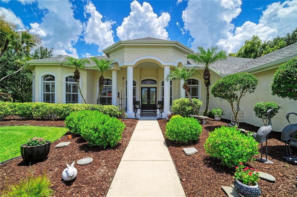 The exterior of a single-story house features a columned entryway, a concrete walkway, and landscaping — 2362 LITTLE COUNTRY ROAD, PARRISH, FL