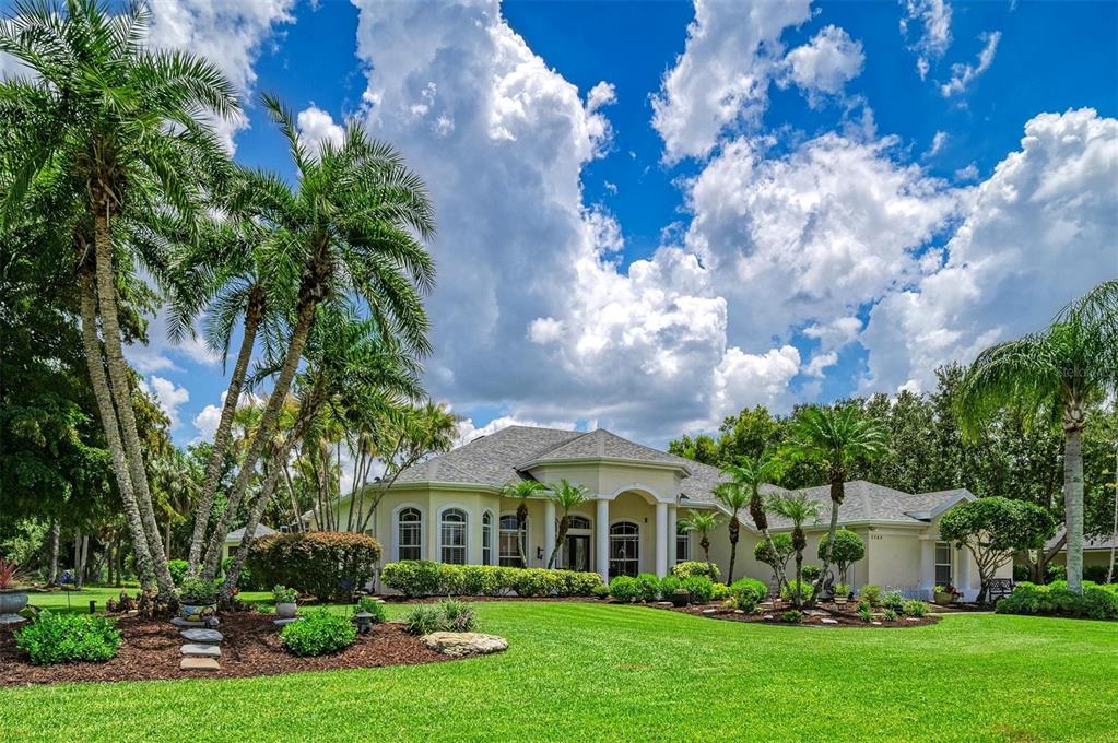 A single-story house with a light-colored exterior, arched windows, and a large front lawn — 2362 LITTLE COUNTRY ROAD, PARRISH, FL