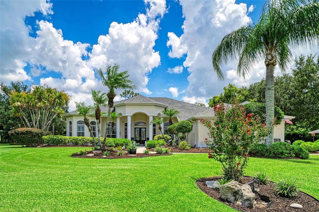 A single-story house with a columned entryway, palm trees, and a large green lawn — 2362 LITTLE COUNTRY ROAD, PARRISH, FL