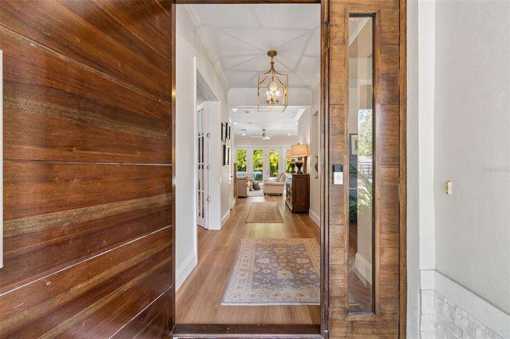 A view through an open wooden front door into a hallway with light wood flooring — 4601 S ESPERANZA AVENUE, TAMPA, FL