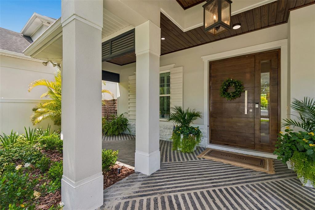 A covered front porch features a wood-paneled ceiling, striped flooring, and a modern wooden door — 4601 S ESPERANZA AVENUE, TAMPA, FL