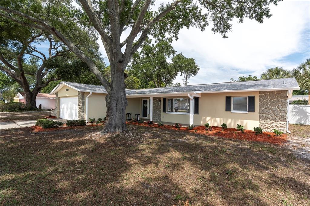 An open-concept kitchen and living room featuring a breakfast bar, sectional sofa, and ceiling fan — 6860 14TH WAY S, ST PETERSBURG, FL