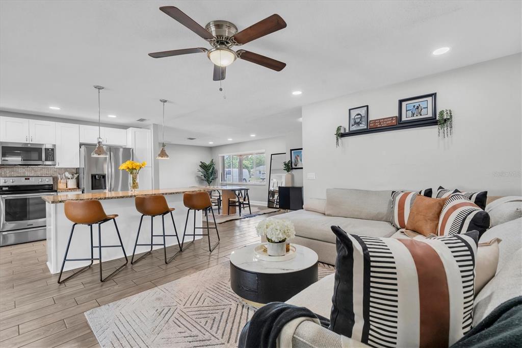 A kitchen features white cabinets, granite countertops, a central island with barstools, and tile flooring — 6860 14TH WAY S, ST PETERSBURG, FL
