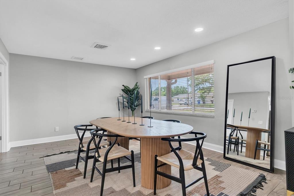 A dining area with wood-look tile flooring, a white console table, and a folding treadmill — 6860 14TH WAY S, ST PETERSBURG, FL