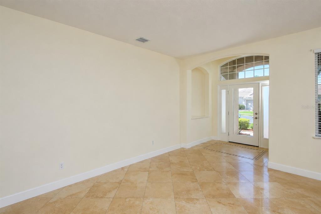 A bright room with beige walls, tile flooring, and a glass-paneled front door with sidelights — 6945 74TH STREET CIRCLE E, BRADENTON, FL