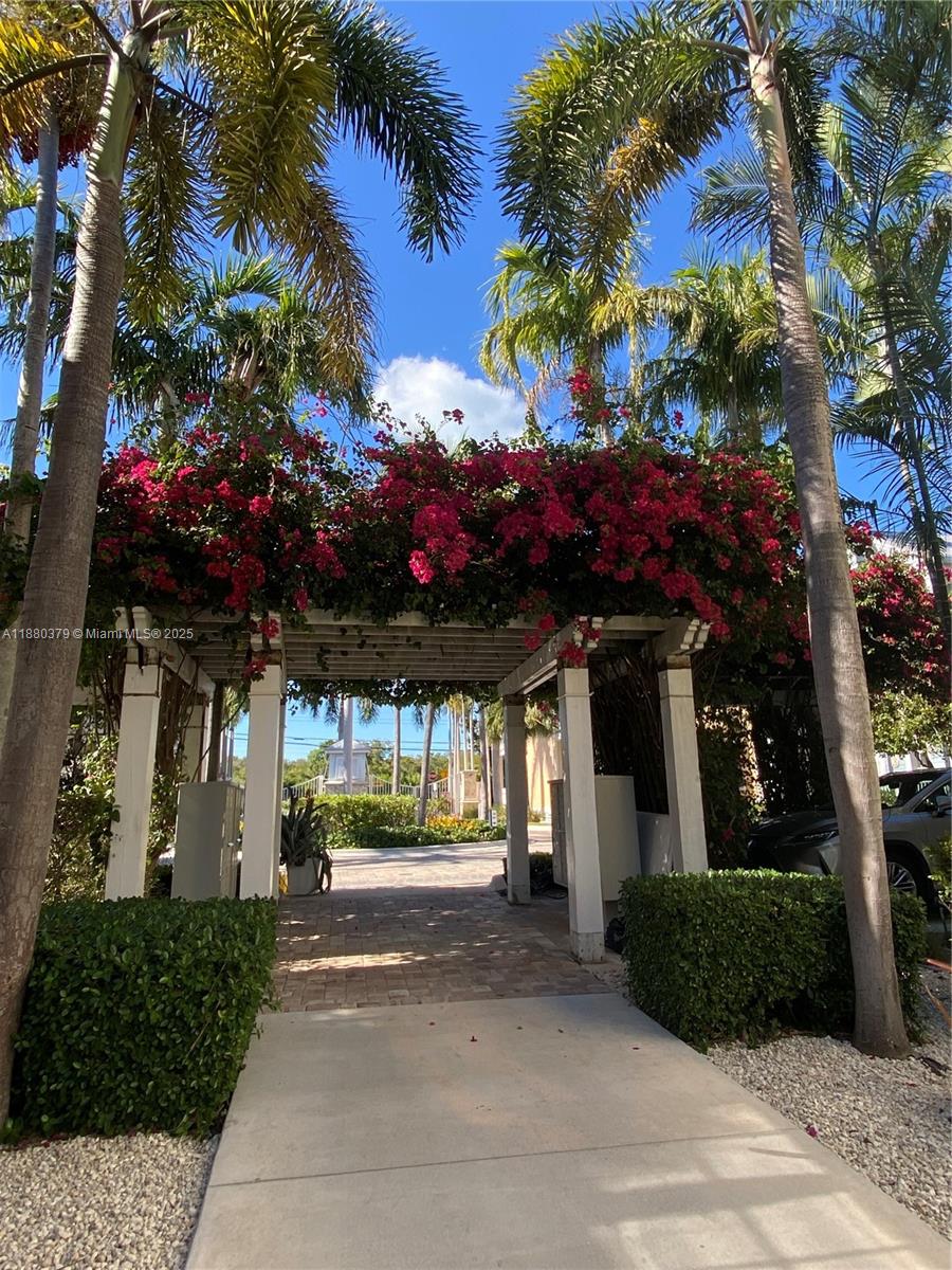 A paved walkway leads through a wooden pergola covered in vibrant pink bougainvillea flowers — 111 Anglers Way, Islamorada FL 33036, ISLAMORADA, FL