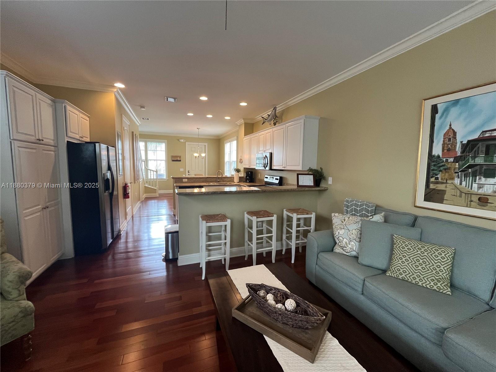 This open-concept living room features hardwood floors, a kitchen island with bar seating, and cabinetry — 111 Anglers Way, Islamorada FL 33036, ISLAMORADA, FL