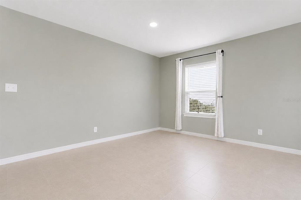 An empty room with light gray walls, tile flooring, and a single window with curtains — 10624 MASSIMO DRIVE, WIMAUMA, FL
