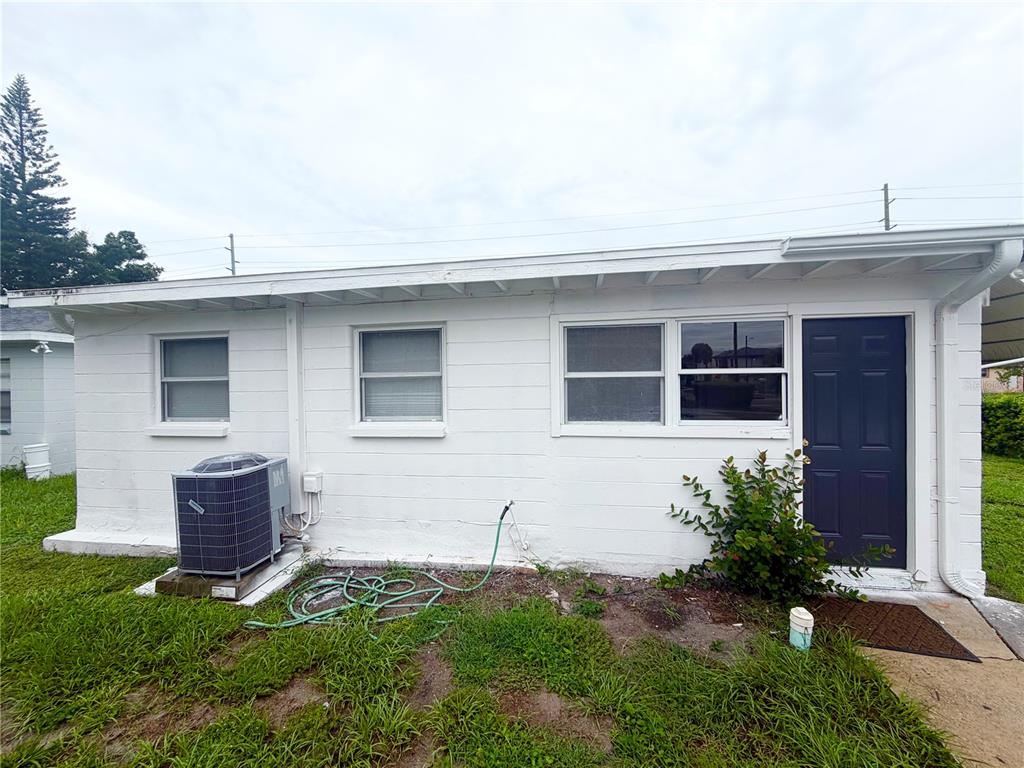 The exterior of a white concrete block building features a dark door and air conditioning unit — 1502 W GRACE STREET, TAMPA, FL