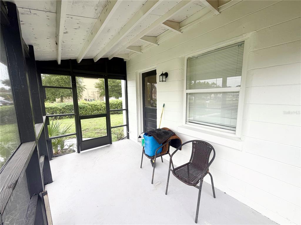 A screened-in porch features a white wall, a window with blinds, and a dark chair — 1502 W GRACE STREET, TAMPA, FL