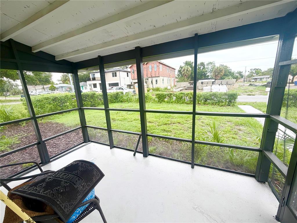 A screened-in porch features a gray floor, dark framing, and a view of a grassy yard — 1502 W GRACE STREET, TAMPA, FL