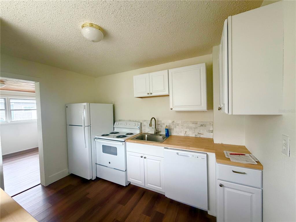 A kitchen features white cabinets, a butcher block countertop, white appliances, and wood-look flooring — 1502 W GRACE STREET, TAMPA, FL