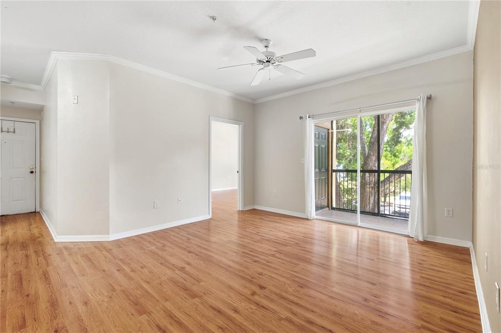 An empty living room features wood-look flooring, a ceiling fan, and a sliding glass balcony door — 5618 PINNACLE HEIGHTS CIRCLE UNIT 206, TAMPA, FL