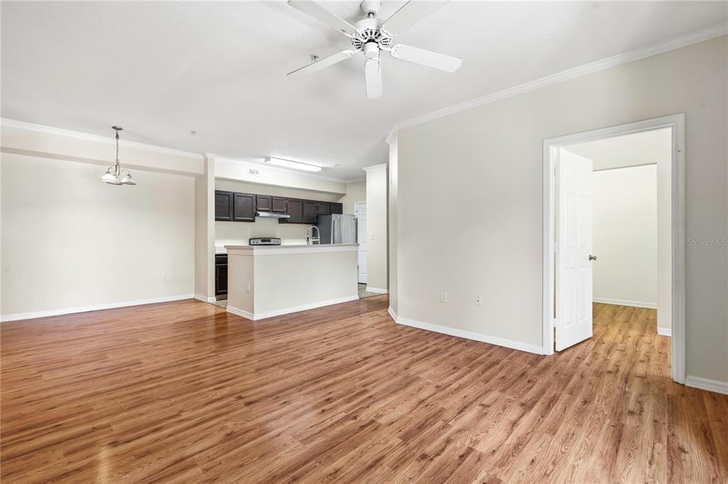 An open-concept living area features wood-look flooring, a ceiling fan, and an adjacent kitchen — 5618 PINNACLE HEIGHTS CIRCLE UNIT 206, TAMPA, FL