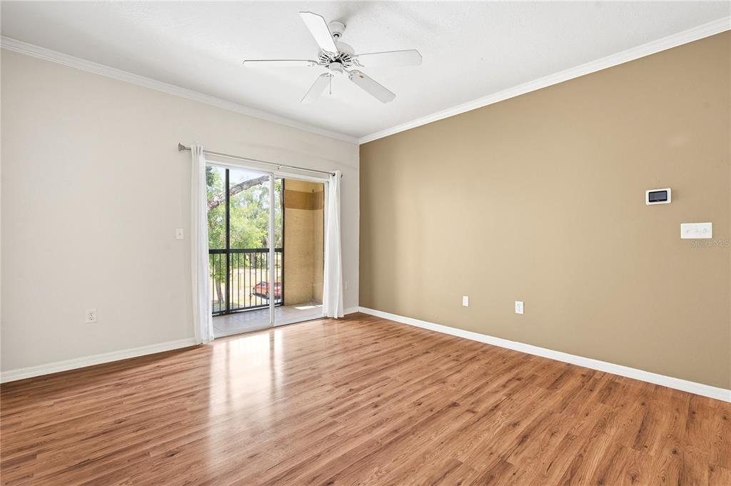 An empty room with wood-look flooring, a ceiling fan, and a sliding glass balcony door — 5618 PINNACLE HEIGHTS CIRCLE UNIT 206, TAMPA, FL