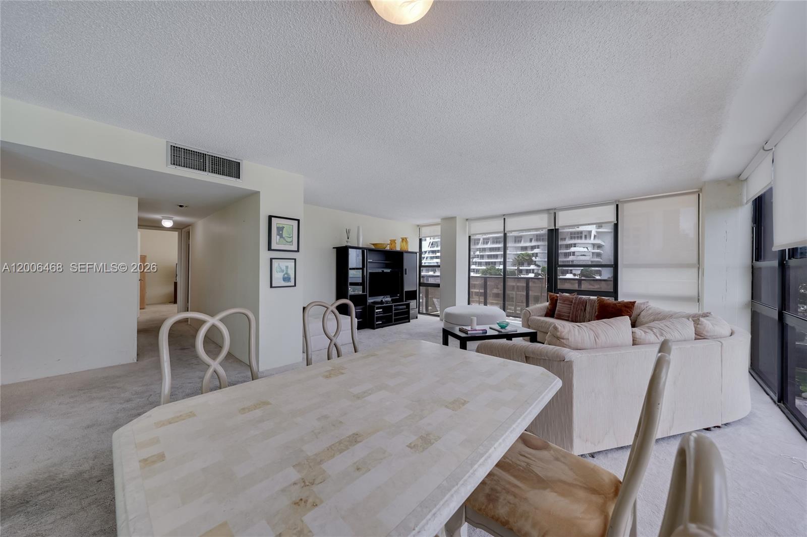 A dining area with a stone-topped table opens into a living room with floor-to-ceiling windows — 600 NE 36th St # 421, Miami FL 33137, MIAMI, FL