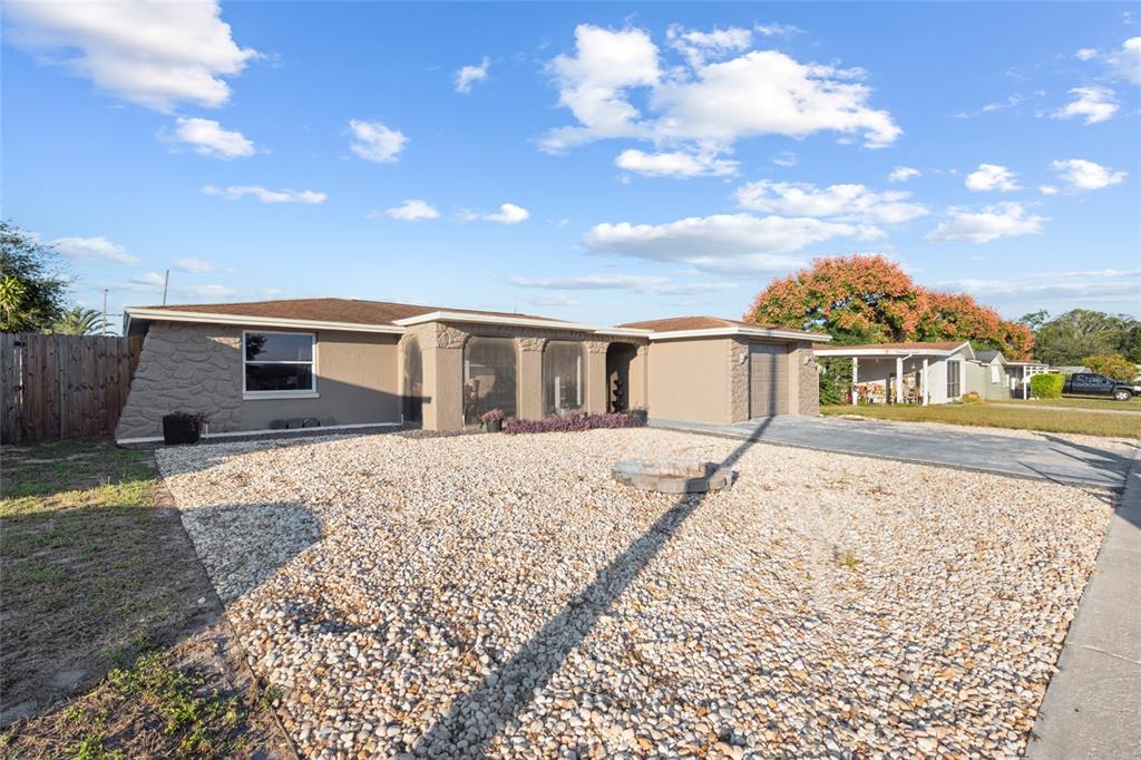 A single-story house with a rock-faced exterior, a gravel front yard, and a paved driveway — 5633 ANDREA DRIVE, HOLIDAY, FL
