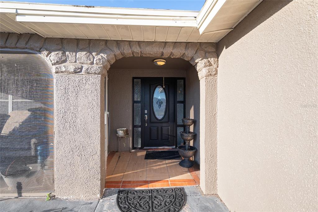 The exterior entryway features a stone-arched porch, a black front door, and tiled flooring — 5633 ANDREA DRIVE, HOLIDAY, FL