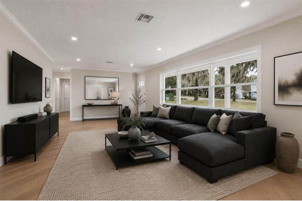 A living room features a dark sectional sofa, a black coffee table, and large windows — 1310 E CROOKED LAKE DRIVE, EUSTIS, FL
