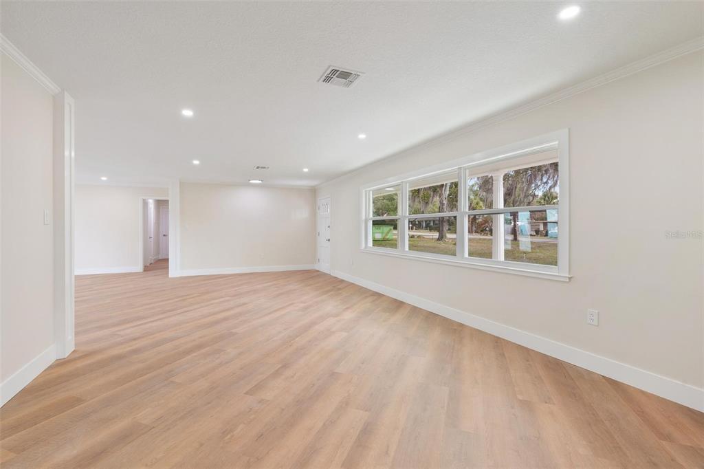 An empty room with light wood-look flooring, white walls, and a large window — 1310 E CROOKED LAKE DRIVE, EUSTIS, FL