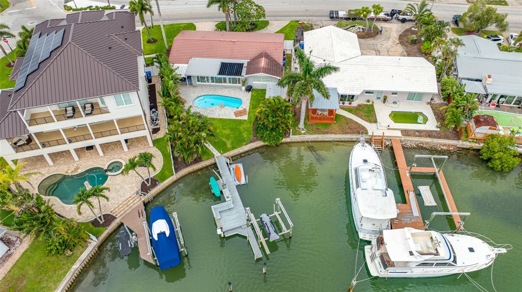 An aerial view shows three waterfront houses with swimming pools and private boat docks — 560 79TH STREET S, ST PETERSBURG, FL
