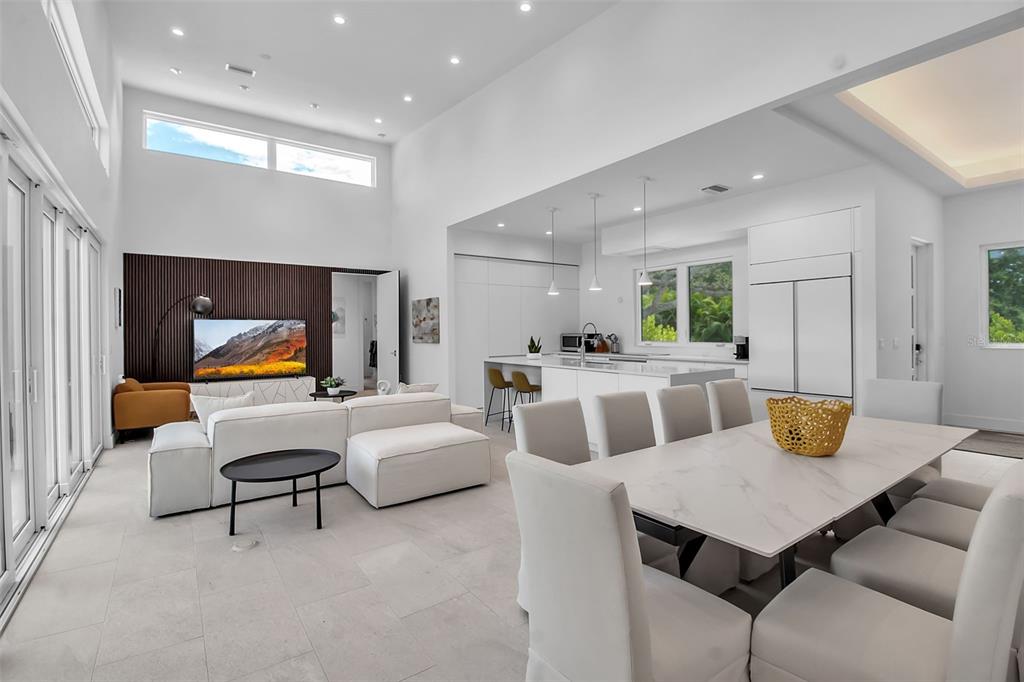 A modern open-concept living and dining area with high ceilings, white tile floors, and cabinetry — 2231 WOOD STREET, SARASOTA, FL