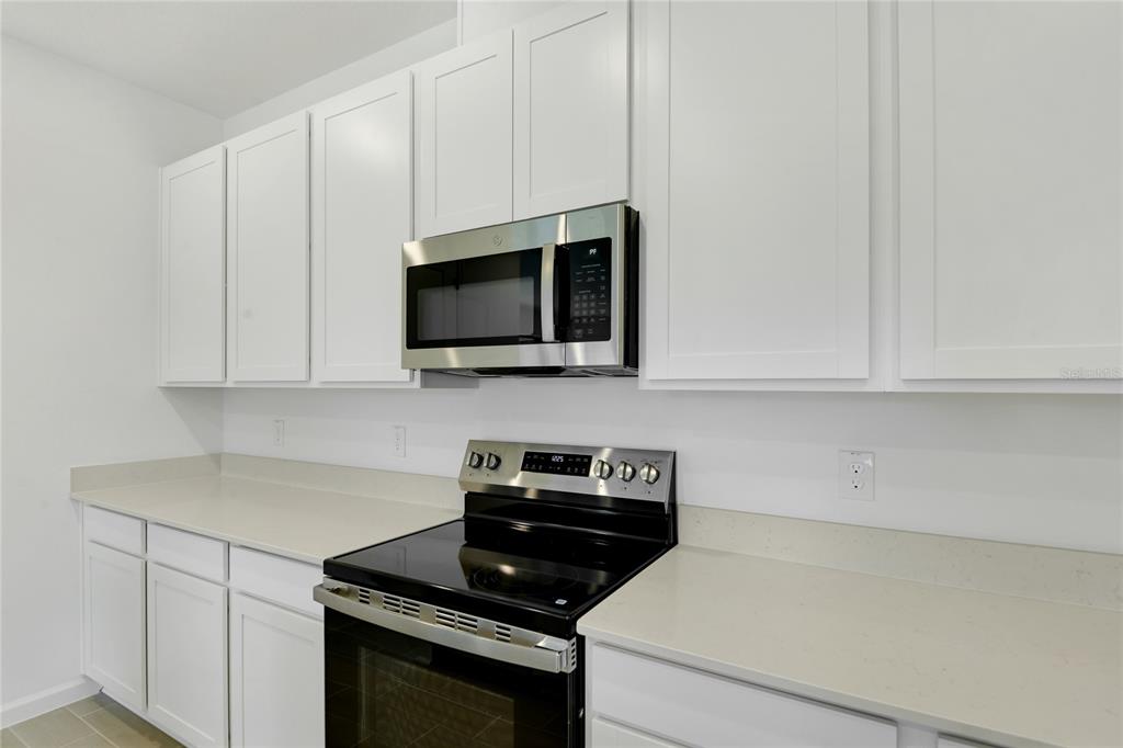 A kitchen features white cabinets, stainless steel appliances, and light-colored countertops — 1766 CARNELIAN STREET, DELAND, FL