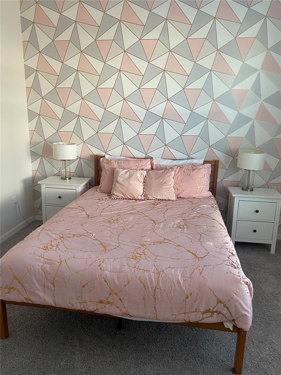 A bedroom features a bed with pink marble bedding against a geometric patterned accent wall — 1523 CAREY PALM CIRCLE, KISSIMMEE, FL