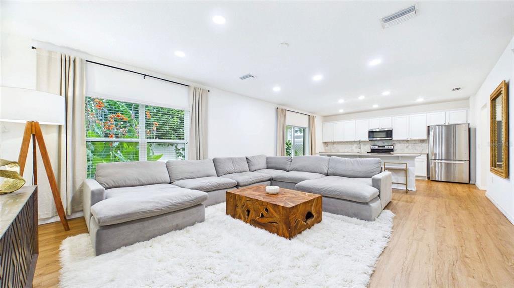 A living room with a large gray sectional, wooden coffee table, and an open kitchen — 3802 E CURTIS STREET, TAMPA, FL