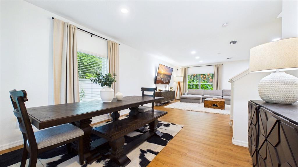 A dining area with a wooden table and bench leads into a living room — 3802 E CURTIS STREET, TAMPA, FL