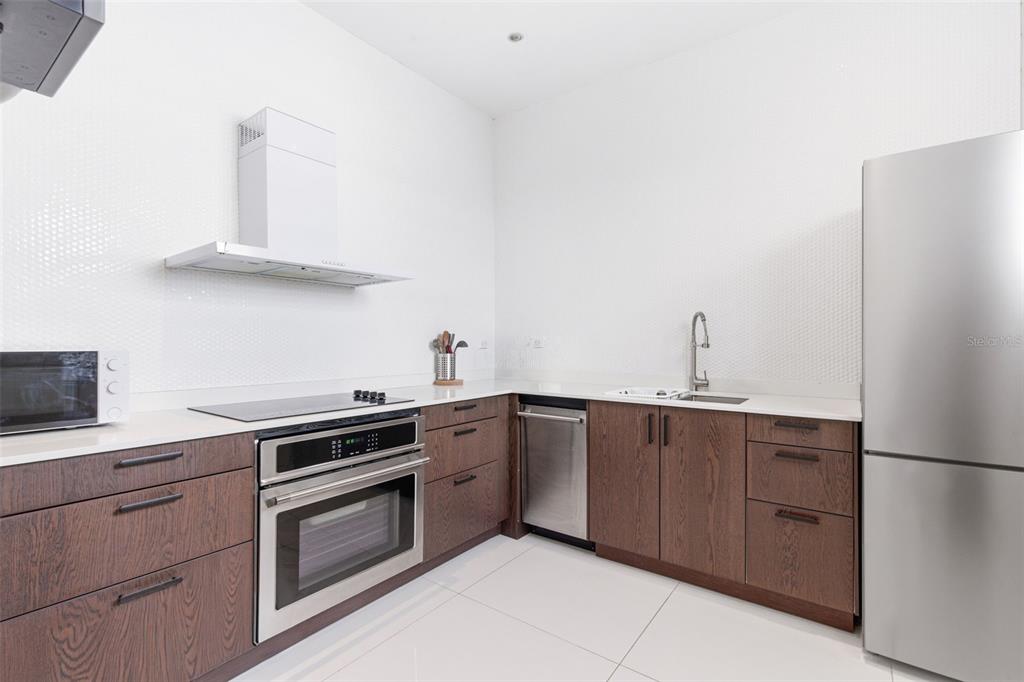 A modern kitchen features dark wood cabinetry, stainless steel appliances, and white countertops — 56 CALLE F KRUG CONDADO UNIT 3, SAN JUAN, PR